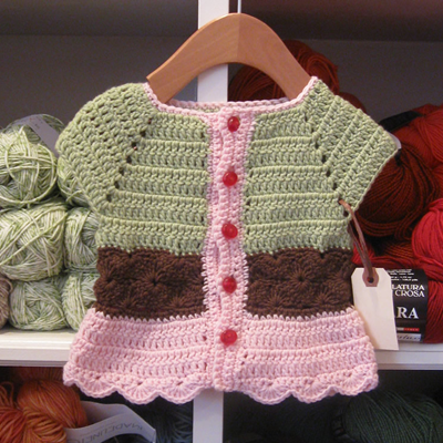 Spumoni Baby Sweater — a crocheted baby cardigan in pink, brown, and green stripes